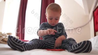一个可爱的婴儿<strong>点击</strong>智能<strong>手机</strong>，坐在大床上，慢动作